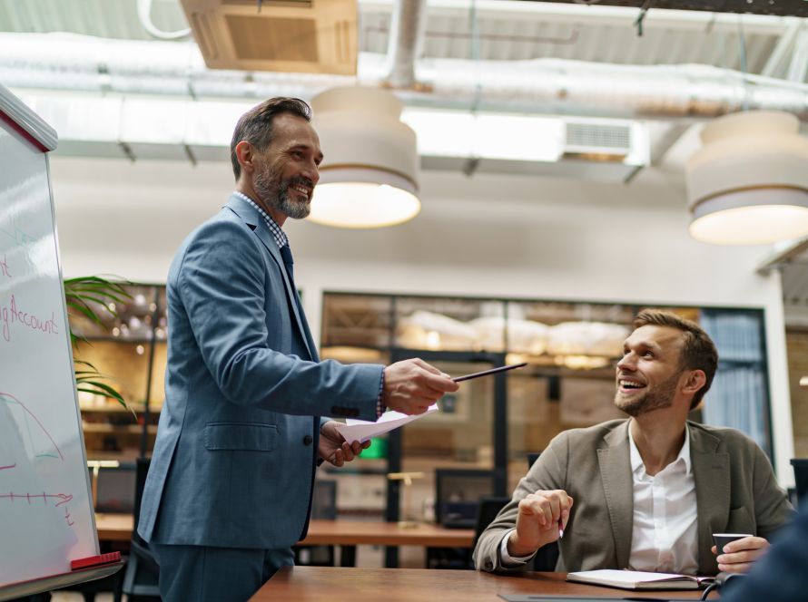 Mature business coach or speaker make flip chart presentation to diverse businesspeople at meeting