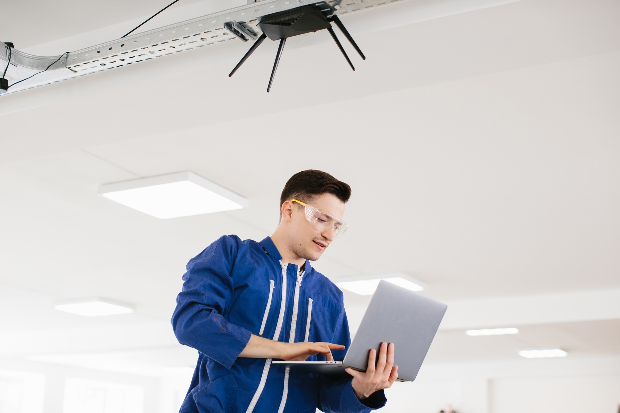 Technician using laptop installing surveillance system in office building
